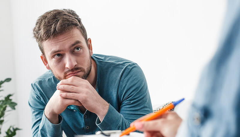 語学学校で先生の話を聞く不安な男性